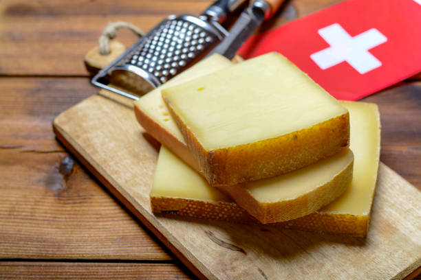 assortment of swiss cheeses emmental or emmentaler medium-hard cheese with round holes, gruyere, appenzeller and raclette used for traditional cheese fondue and gratin and flag of switzerland - cheese emmental cheese switzerland grated imagens e fotografias de stock