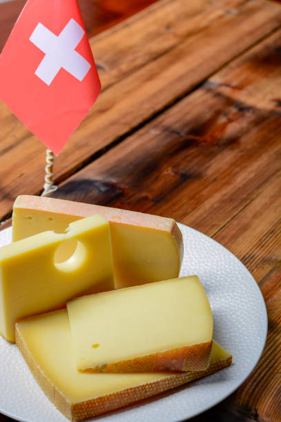 assortment of swiss cheeses emmental or emmentaler medium-hard cheese with round holes, gruyere, appenzeller and raclette used for traditional cheese fondue and gratin and flag of switzerland - cheese emmental cheese switzerland grated imagens e fotografias de stock