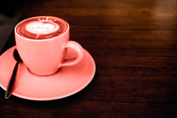 Tasty cappuccino is on the wooden texture table with love art. Living Coral color of the year 2019.