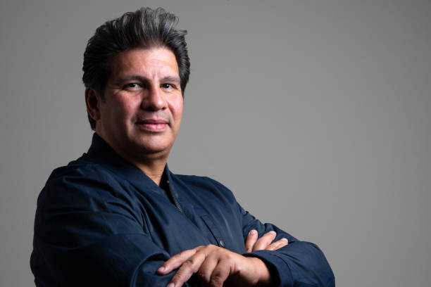 Smiling hispanic mature adult man posing on gray background, he is a professional influencer