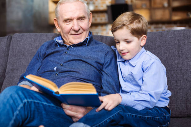 istock Pleasant little boy reading a book with his grandfather 1078233526