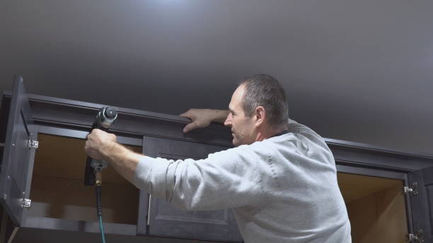istock Carpenter brad using nail gun to Crown Moulding on kitchen cabinets framing trim 1078243630