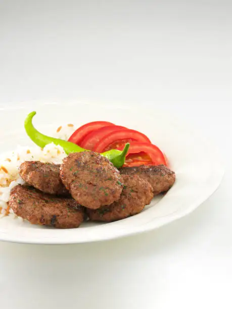 Meatball or turkish köfte with rice and green pepper and tomatoes in plate.