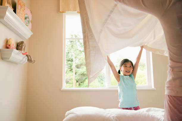 figlia e madre asiatiche che fanno il letto a casa - bed child smiling people foto e immagini stock