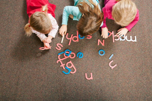 children playing with letter shapes in grade school classroom - dictionary alphabet letter text imagens e fotografias de stock