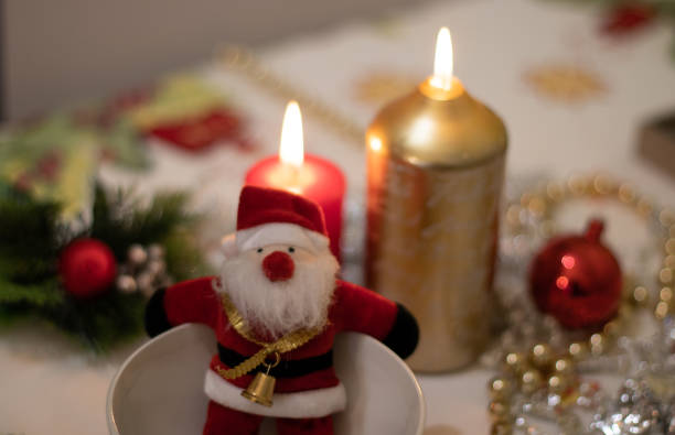istock Santa Claus doll inside a bowl with on a Christmas tablecloth with candles 1078259104