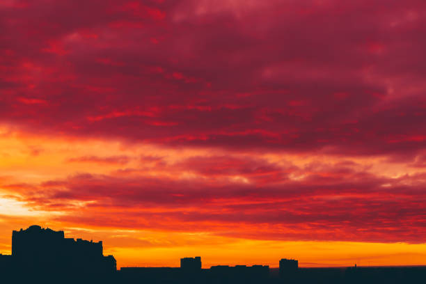 istock Cityscape with vivid surrealistic dawn. Amazing warm dramatic cloudy sky above dark silhouettes of city buildings. Orange sunlight. Atmospheric background of sunrise in overcast weather. Copy space. 1078265580