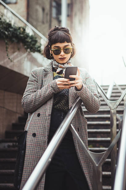 Winter portrait of a young woman in the city texting stock photo