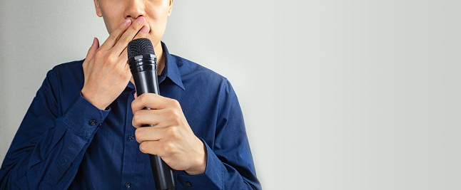 Man covering mouth, holding microphone