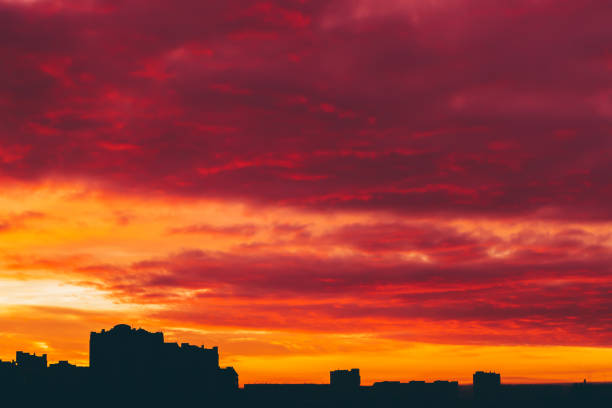 istock Cityscape with vivid surrealistic dawn. Amazing warm dramatic cloudy sky above dark silhouettes of city buildings. Orange sunlight. Atmospheric background of sunrise in overcast weather. Copy space. 1078293374