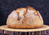 Homemade artisan loaf of sourdough bread broule with crust on a wooden board