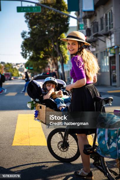 Mom Pushing Kid In Cargo Bike Smiling Back At Camera Stock Photo - Download Image Now