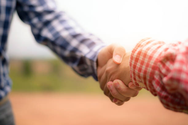 istock Men shaking hands. Side view of two men shaking hands while standing on the site office or farm land,copy space. 1078306806