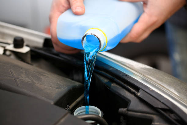 männliche hände halten flasche blau frostschutzmittel in - washing water car cleaning stock-fotos und bilder