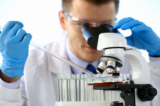 portrait of a young chemist looking in binocular - lubrication infection imagens e fotografias de stock