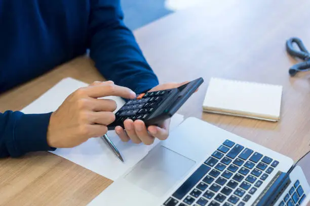 Photo of close up top view of man hand press on calculator counting calculating about monthly expense ,money management concept