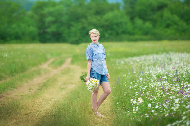 istock Attractive young woman with chamomile bouquet walking through the chamomile field. Active blonde outdoors 1078357938
