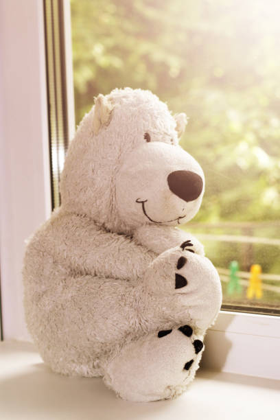istock Big brown teddy bear sitting near window. 1078364784
