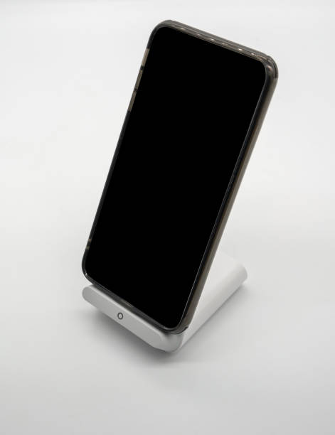 istock Black cellphone charging on modern designed wireless charger stand isolated on white bakcground. 1078378880