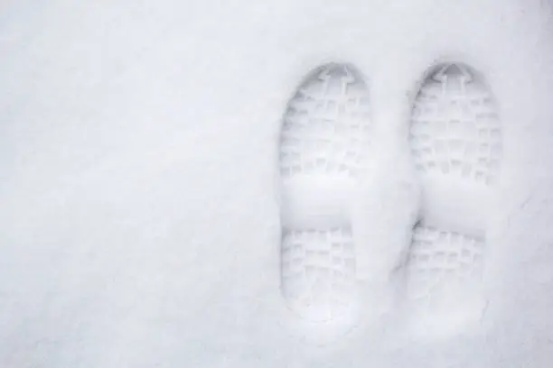 Photo of Human's footprint on a first white snow, top view.