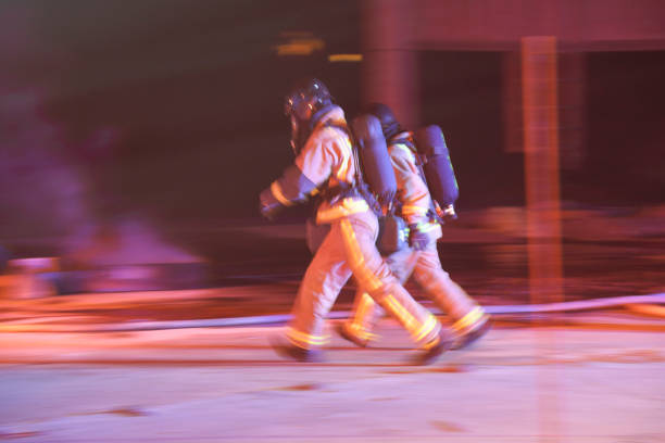 Night shot of a firefighters working on serious traffic accident scene with upside down car, fire engine in background.