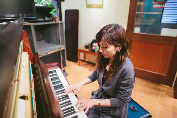 A young female pianist is playing the piano in a jazz bar