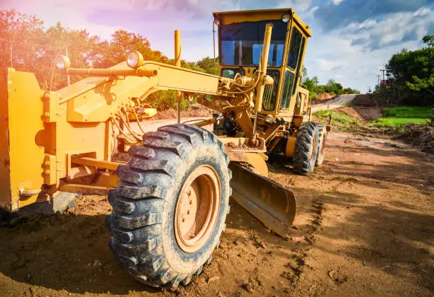 Photo of oad construction with motor grader road / yellow of modern grader