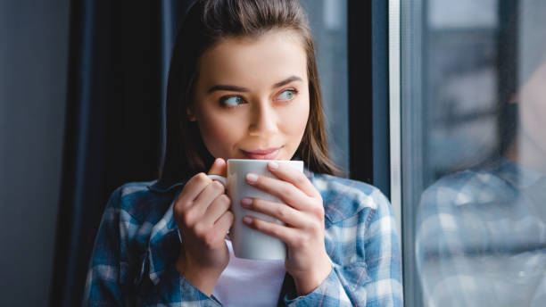 istock beautiful happy girl drinking tea and looking at window 1078413870