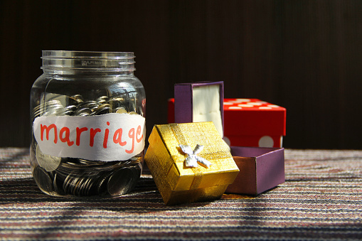 Coins in money jar with marriage label, finance concept