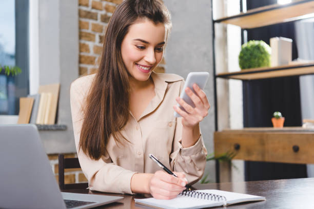 istock beatiful smiling young businesswoman using smartphone while working in office 1078425336