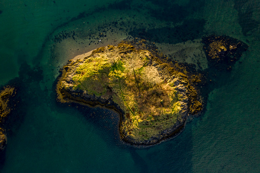 Aerial shot in the morning light of an island located in a fjord/firth in the west highlands of Scotland.