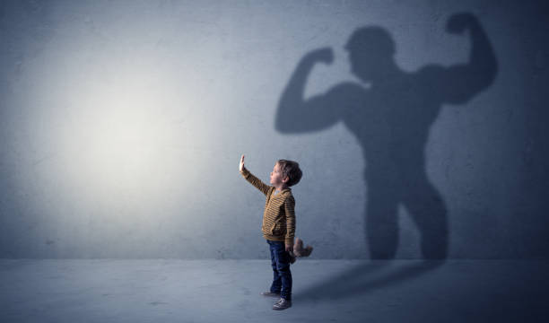 istock Muscleman shadow behind waggish little boy 1078427490
