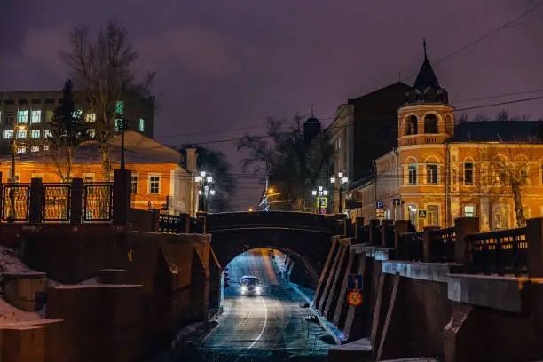 Night winter Voronezh, car moves on the road under Stone Bridge.