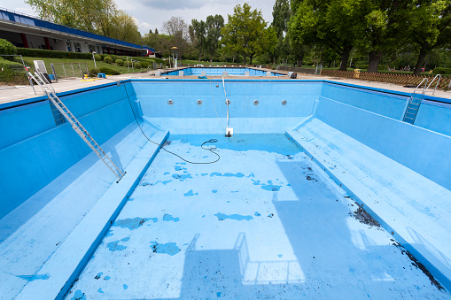 Drained swimming pool. Cleaning equipment, preparing for the summer season - view from above
