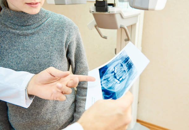 computed tomography of teeth Dental tomography. In the hands of the doctor, an x-ray of the teeth is shown, for a girl standing nearby jaw pain stock pictures, royalty-free photos & images