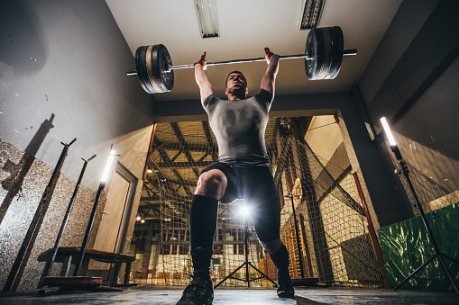 One man, body builder weightlifting in gym alone.