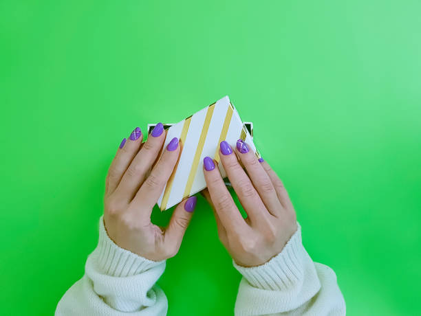 istock female hands manicure, gift box on color paper background 1078449018