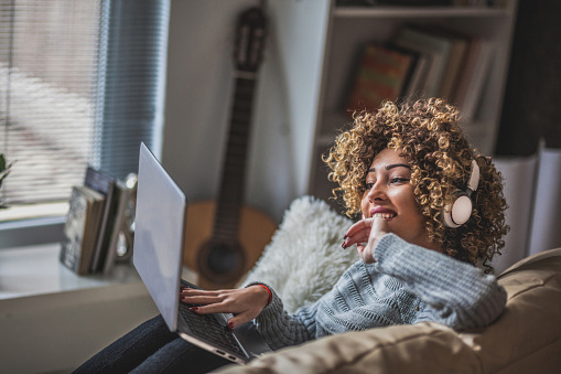 Young girl with laptop sitting in  living room