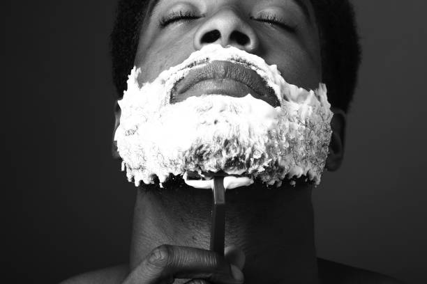 Hipster barber focused on cutting hair in his barber shop. Retro barber shop. Attractive barber cutting hair. Man getting his beard groomed. Black and white photography. Artistic photography.