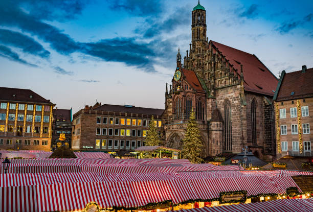 Nuremberg, Germany - December, 05, 2018: Christmas market, the most famous Christkindlesmarkt in the old town of Nuremberg at evening with view of church cathedral Frauenkirche