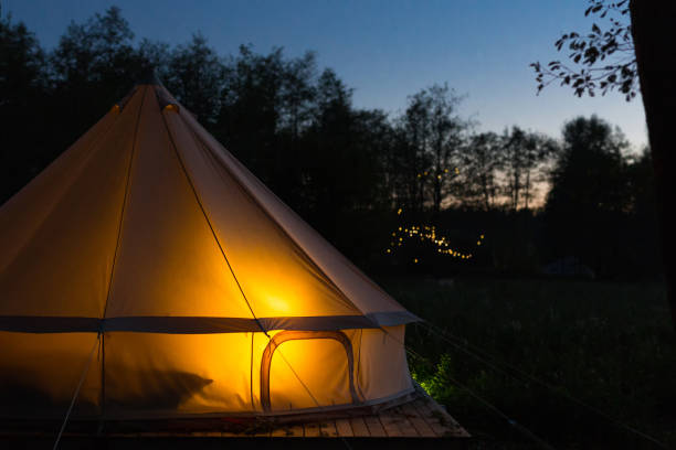 Canvas glamping tent glows at night Glamping bell tent glows at night at forest glamping photos stock pictures, royalty-free photos & images