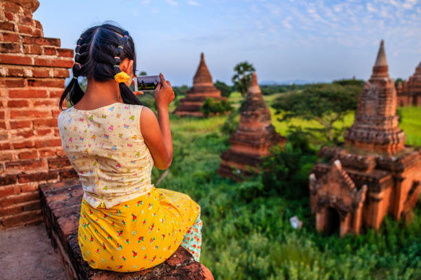 Young Burmese girl with thanaka face paint taking a picture on an ancient temple in Bagan, Myanmar (Burma)