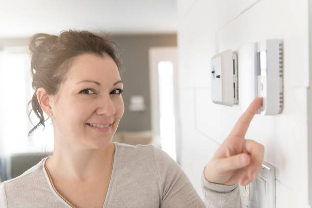 istock A nice woman set the thermostat at house. 1078480962