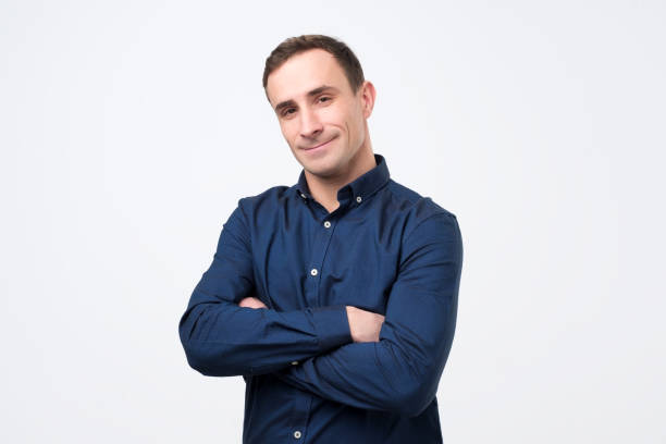 istock Smiling young man standing with arms crossed against gray background 1078482230