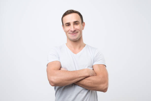 istock Smiling young man standing with arms crossed against gray background 1078483152