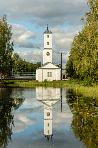 Beautiful tall tower building in Stjärnsund, Sweden. In bright summer sunshine mirroring in water surrounded by green vegetation