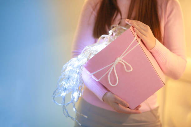 istock A girl with pink gift box and lights. 1078484756