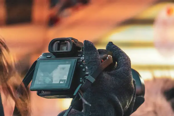 close up female hands holding a photocamera and shoot video in the street