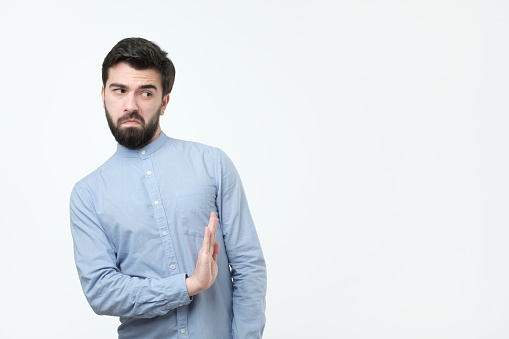 Attractive spanish man with beard shows refusal gesture, e, has sad expression. I do not need this option.