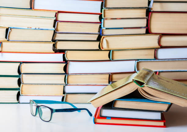 Books and eyeglasses on a wooden table, on purple trendy soft background